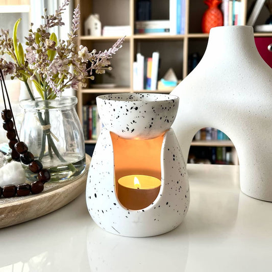 White My Black Dog ceramic tealight burner with black speckles sitting on a desk.