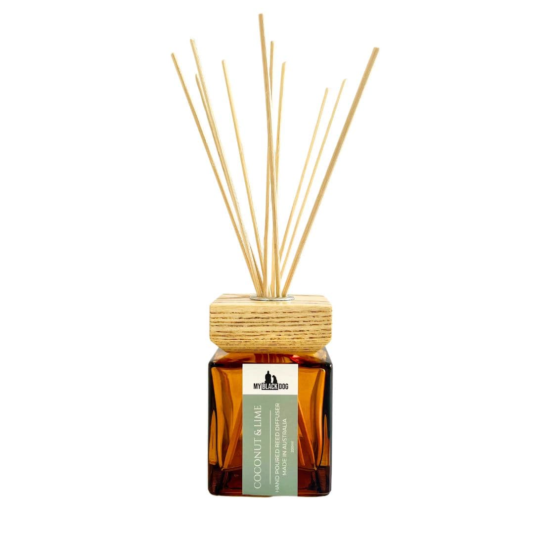 My Black Dog Coconut and Lime reed diffuser in a square amber bottle with wooden lid and reed sticks on a white background.