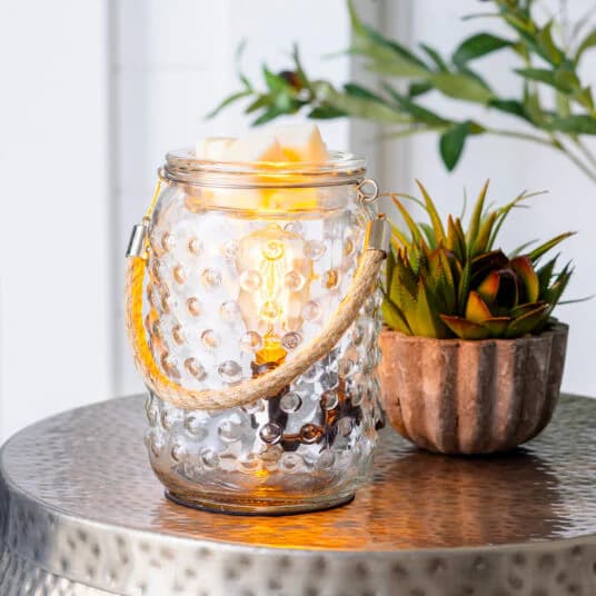 Hobnail & Rope Illumination Wax Melt Warmer sitting on a side table with plant