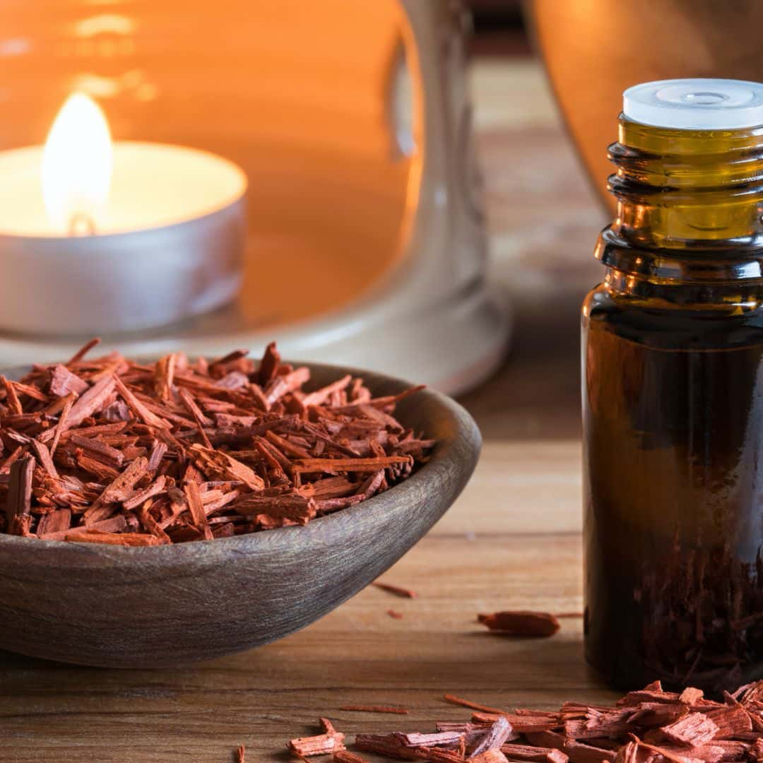 Sandalwood chips in a wooden bow, with an oil bottle and tealight candle burning