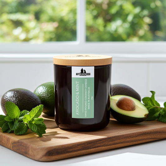 An avocado and mint scented candle sitting on a chopping board with avocados and mint leaves