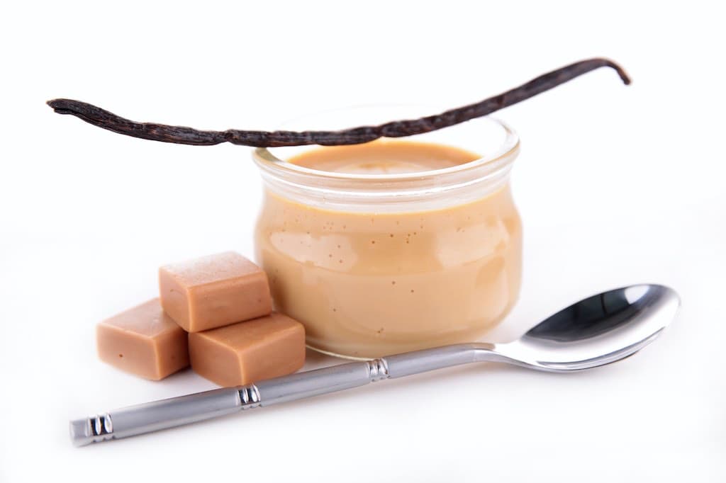 Caramel in jar with vanilla bean and spoon